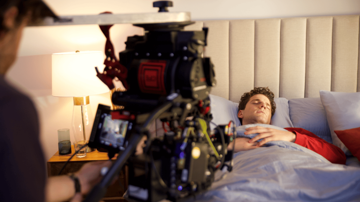 Actor sleeping on the bed while being filmed.