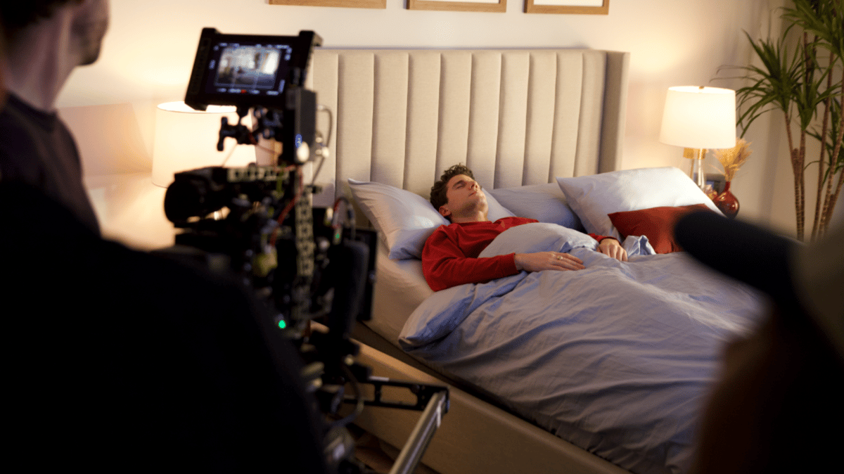 Actor lying down on the bed during a shoot.