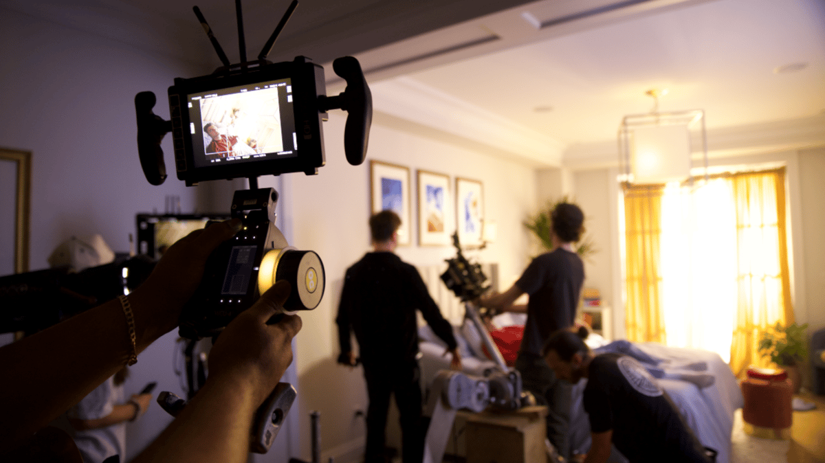 Production team setting up the set while the actor is in bed.