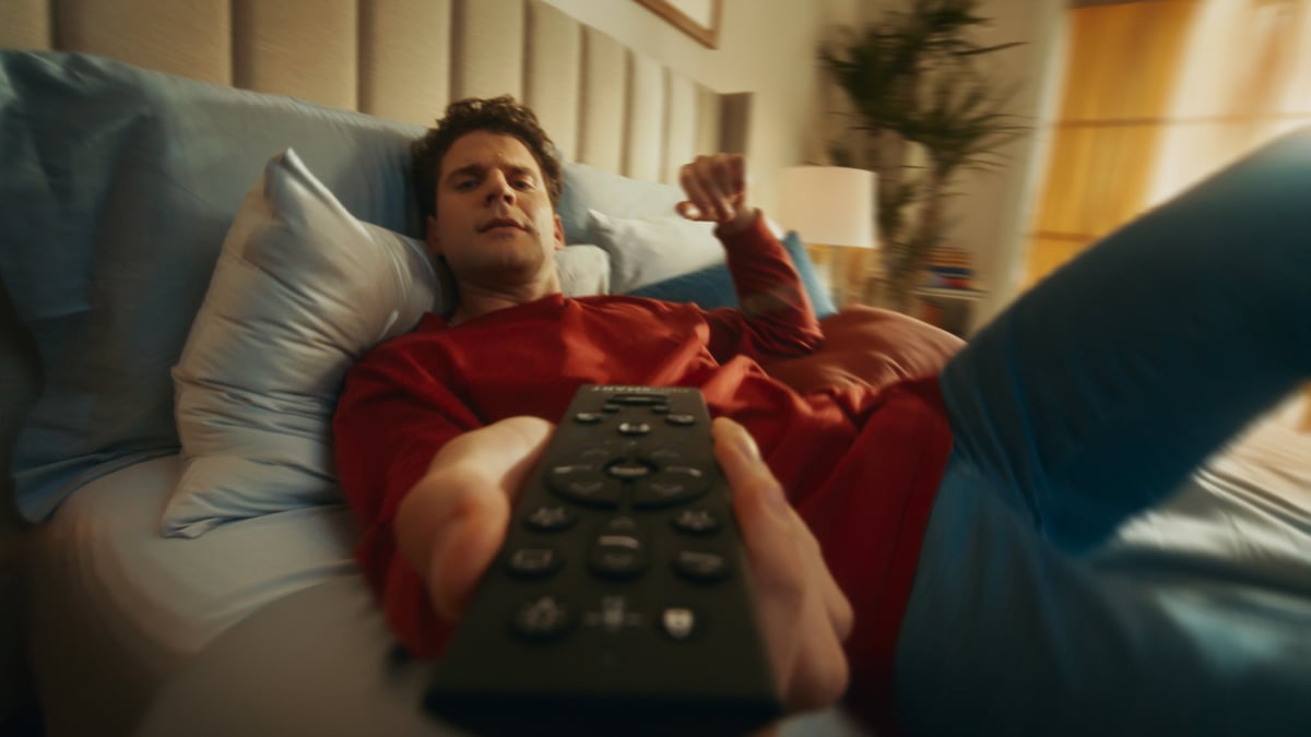 Man lying down in bed holding a remote.