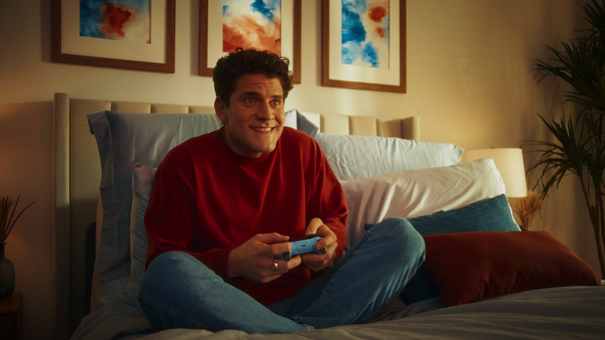 Man sitting comfortably in bed while playing games.
