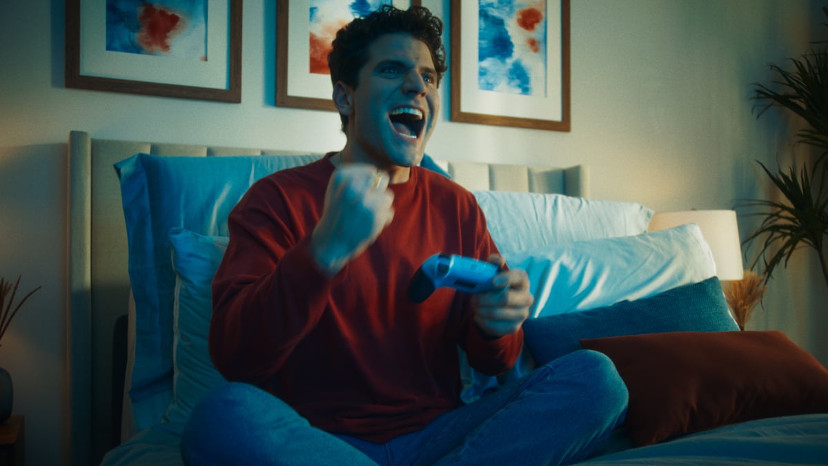 Man extremely happy while playing games in bed.