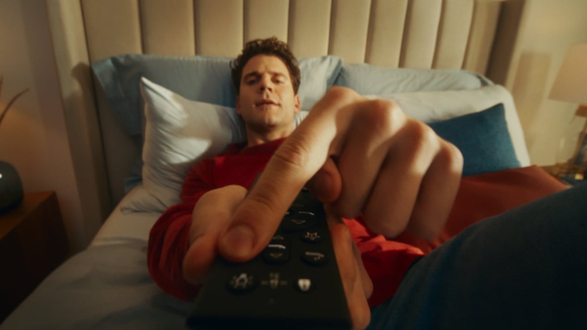Man lying down, pressing the button with complete amusement.