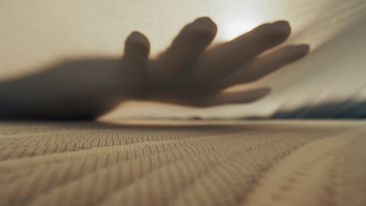 Close-up shot of the surface of a vibrating bed with a hand feeling the vibration.