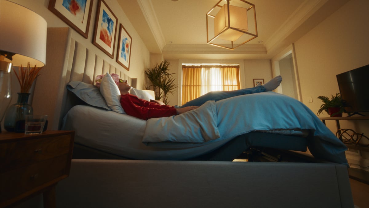 Man lying on the bed in a relaxed, curved position.