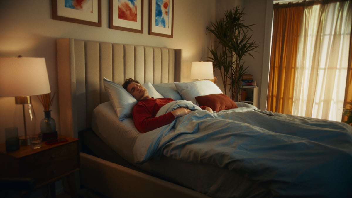 Man sleeping in bed, completely relaxed.