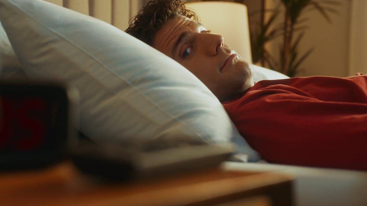 Man looking at the side table with a remote.