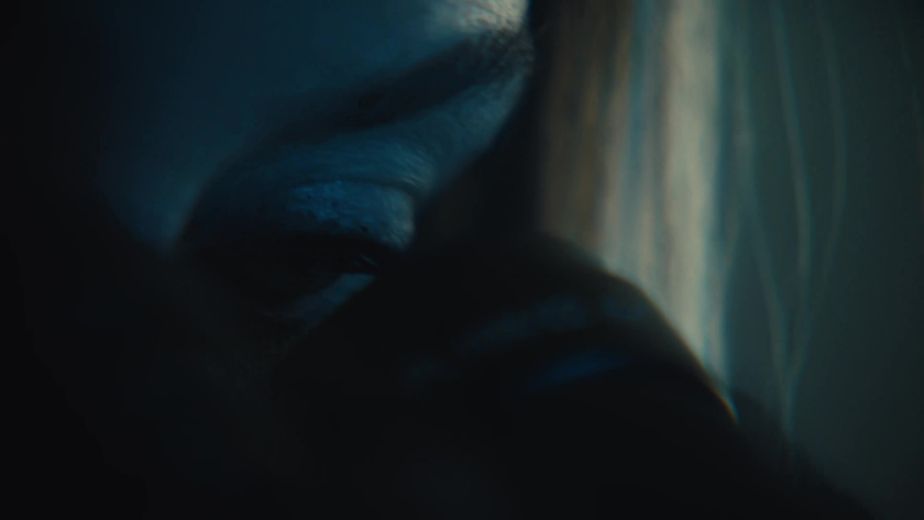 Extreme close-up of an eye peering intently through shadows.