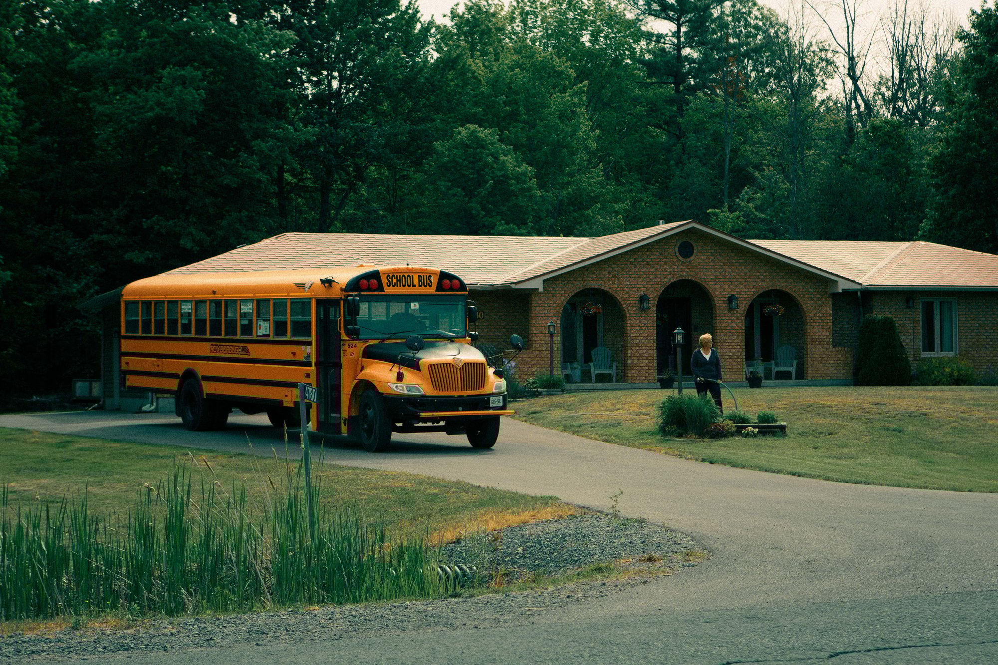 An IC Bus school bus parks in front of a brick residential home at golden hour, representing the trusted daily presence of safe student transportation in communities.