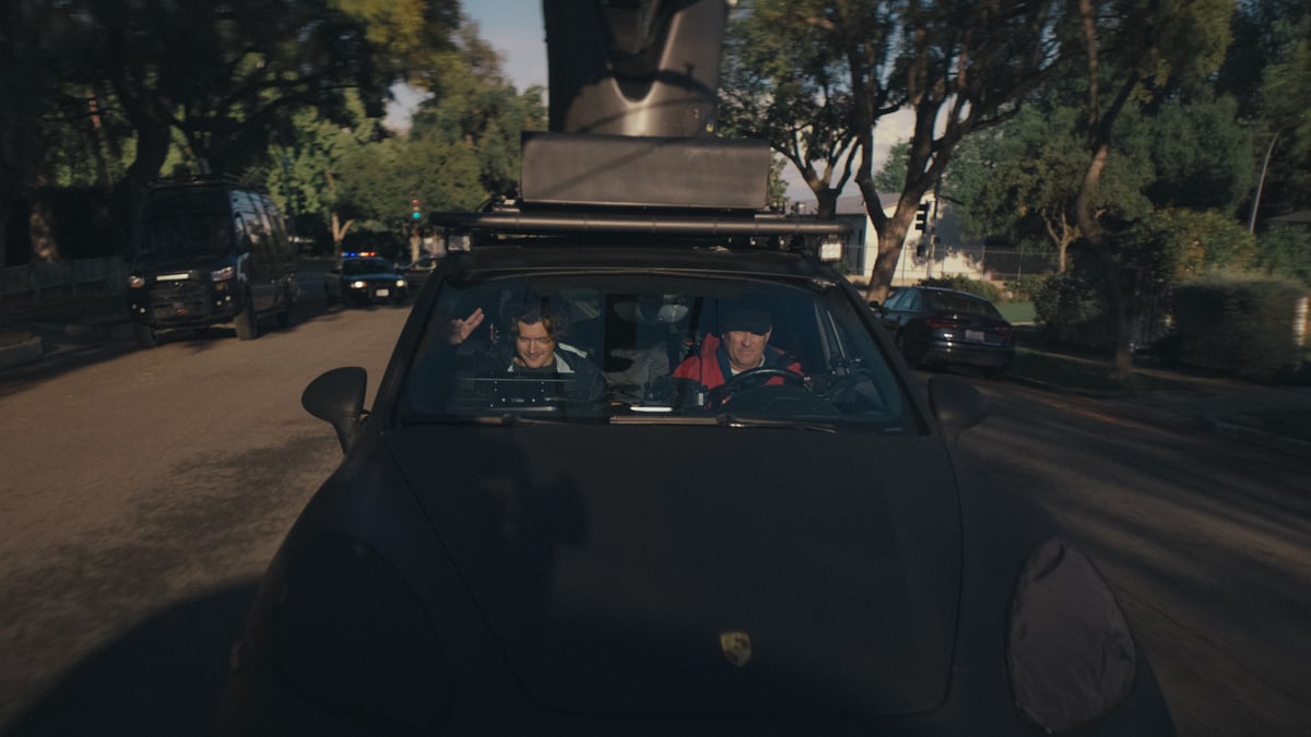 The director and driver are inside a custom car designed for video shooting, and the car is in motion.