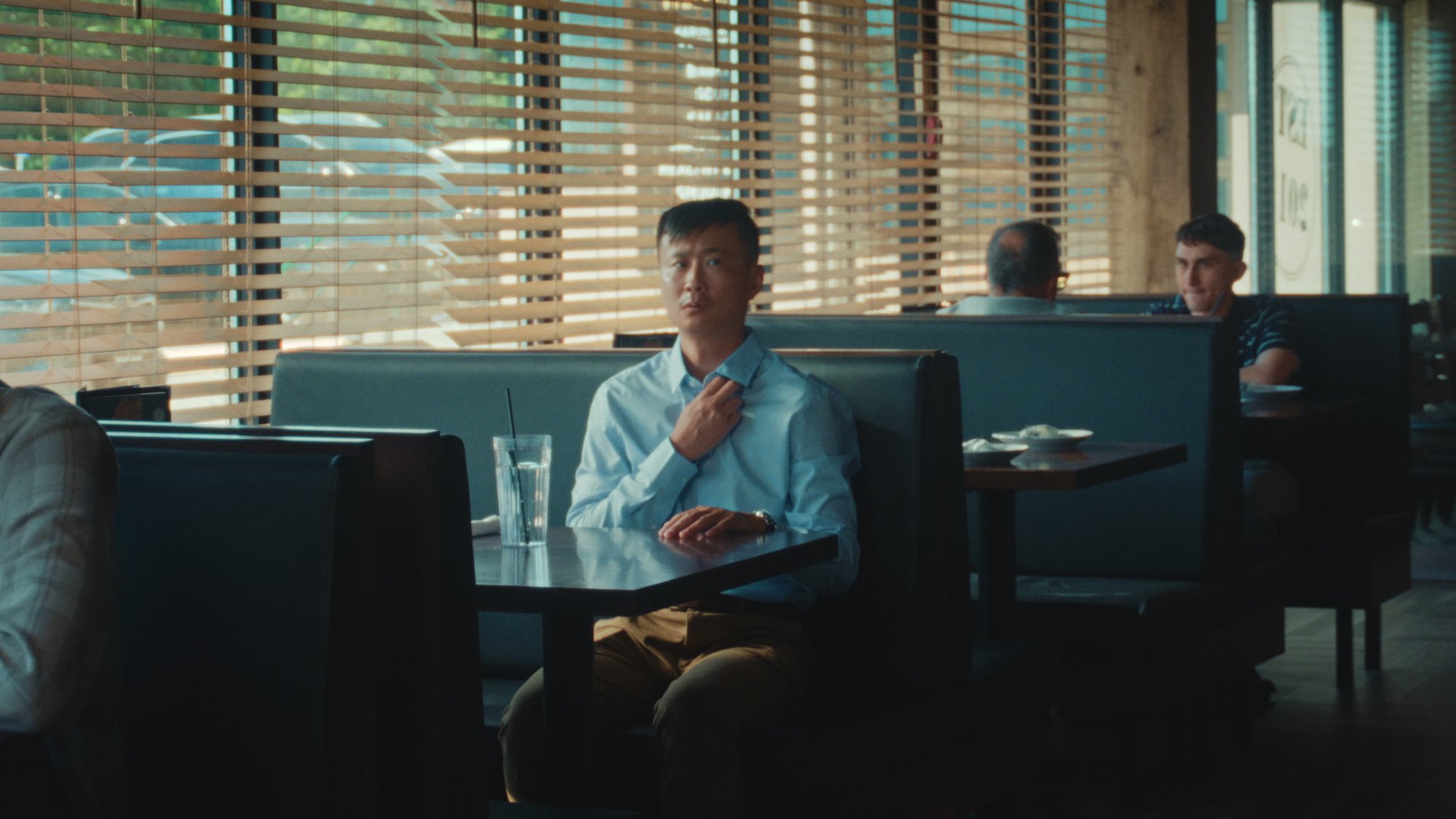 A man seated alone in a booth while waiting for his order