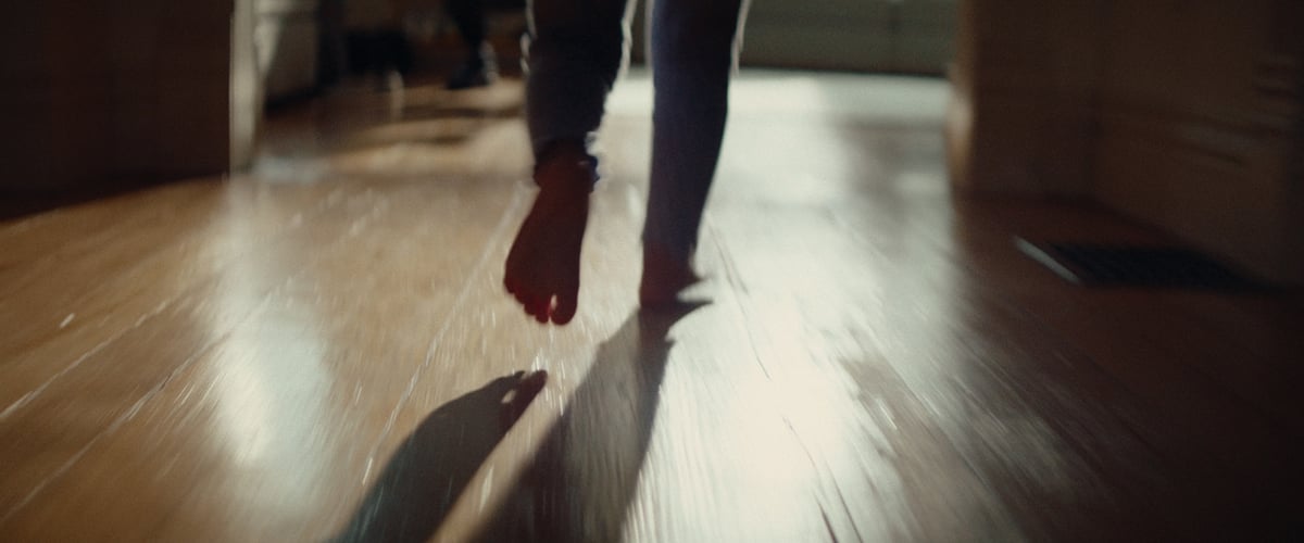  The feet of a child in motion, taking steps toward the door to open it.