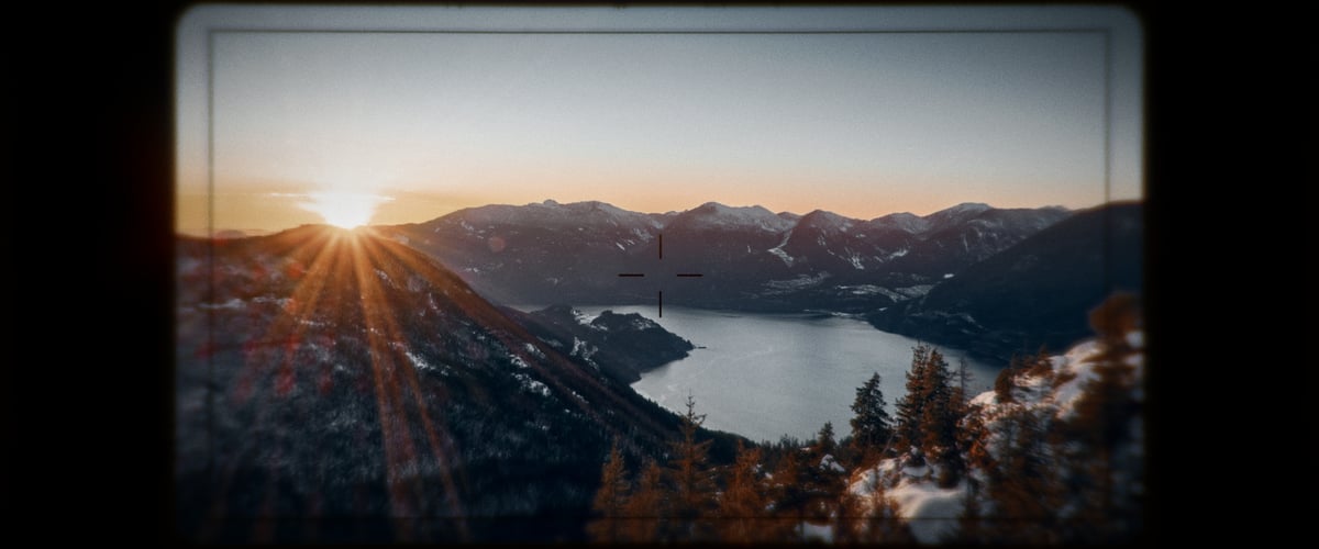 A picturesque lake nestled among mountains under a clear sky with the sun shining brightly.