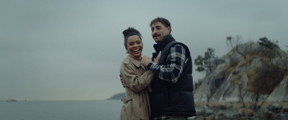 A couple posing by the lakeside with a stunning backdrop.