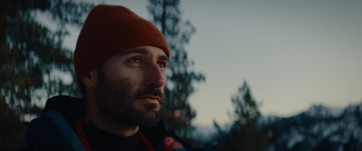 A man gazing to his side amid the stunning snowy mountain scenery.