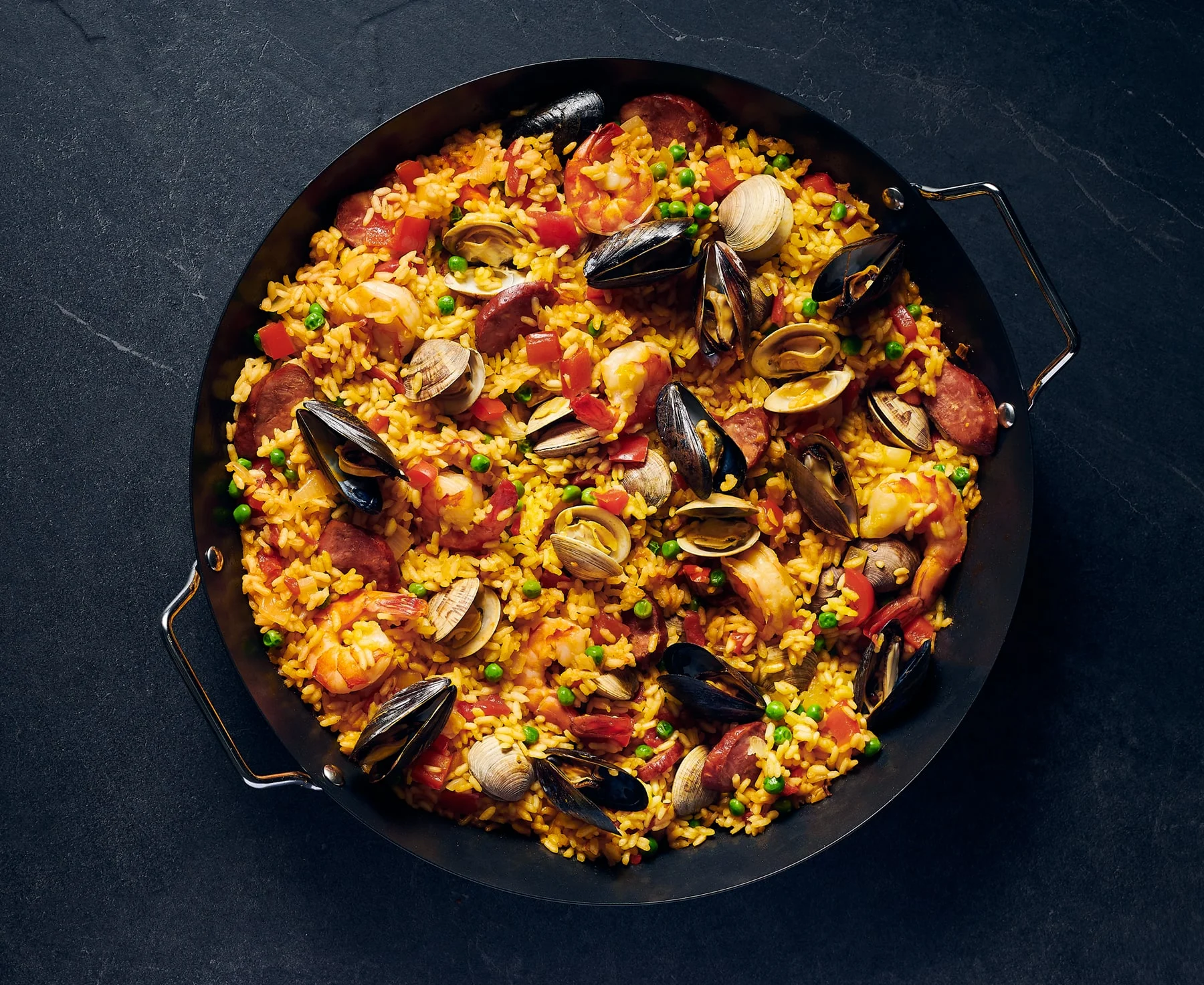 Seafood jambalaya in black pot with black background