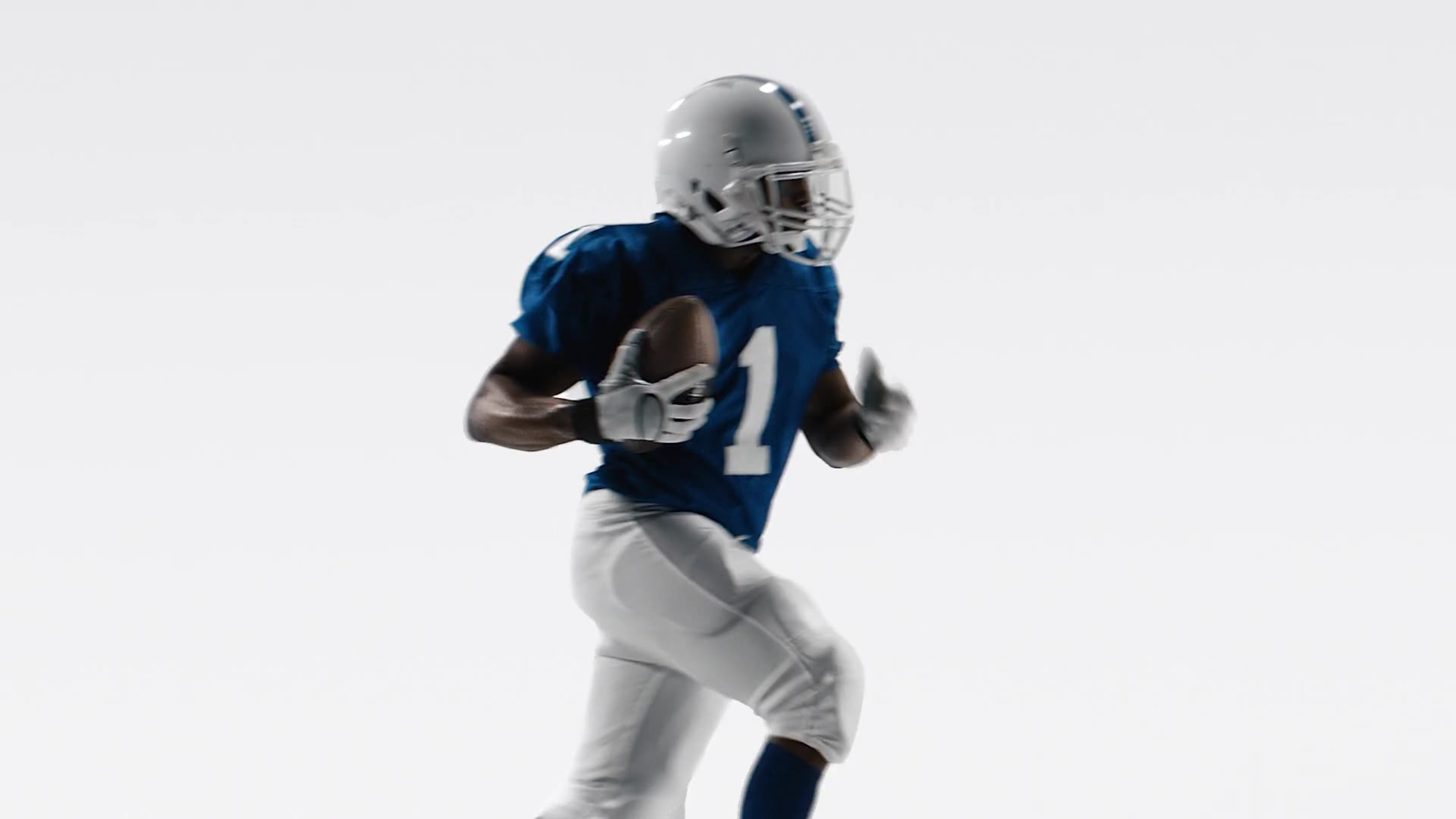 A football player in a blue and white uniform runs with the ball against a stark white background.