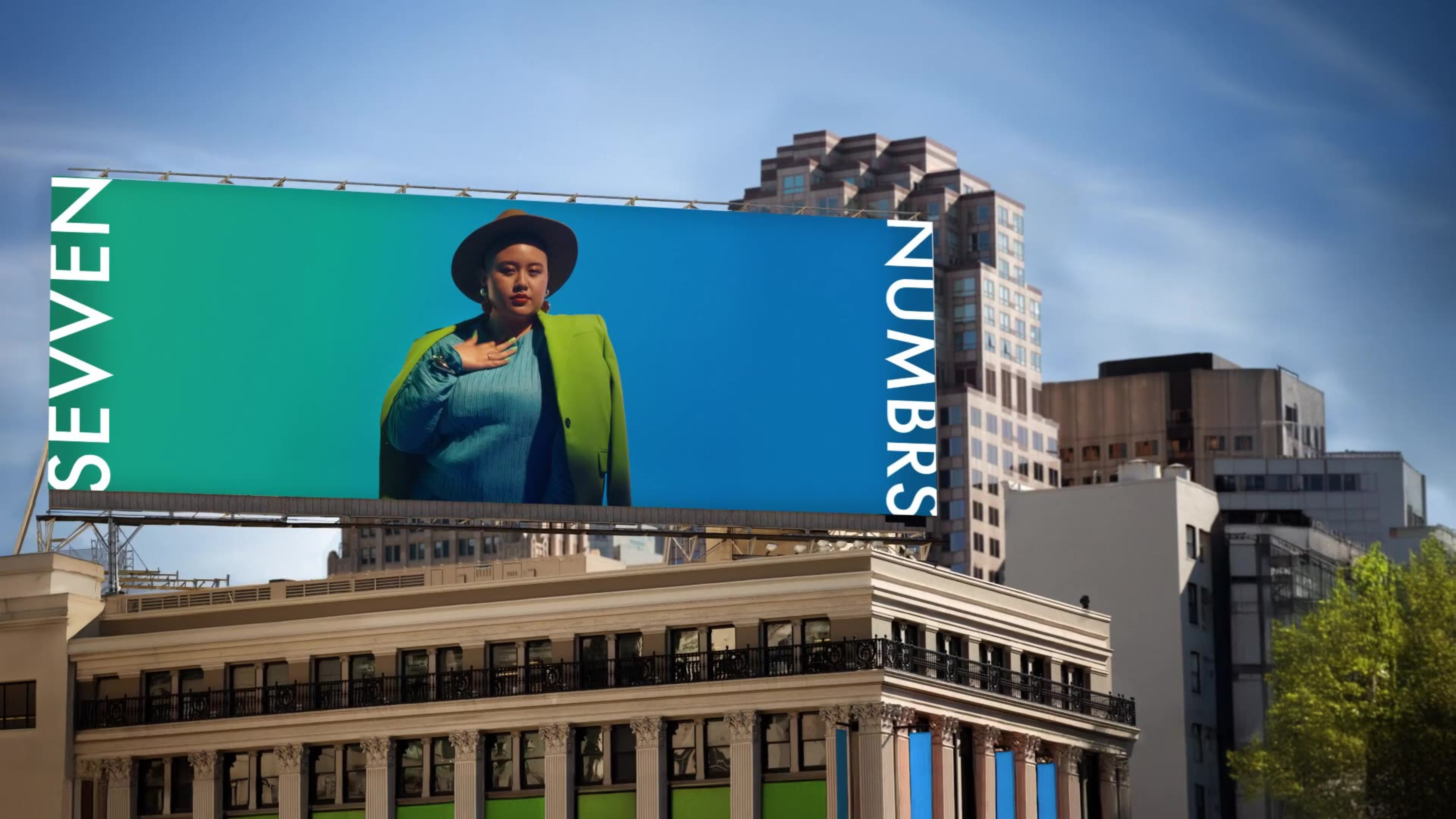 A large urban billboard features a woman in a green blazer and hat alongside the text 