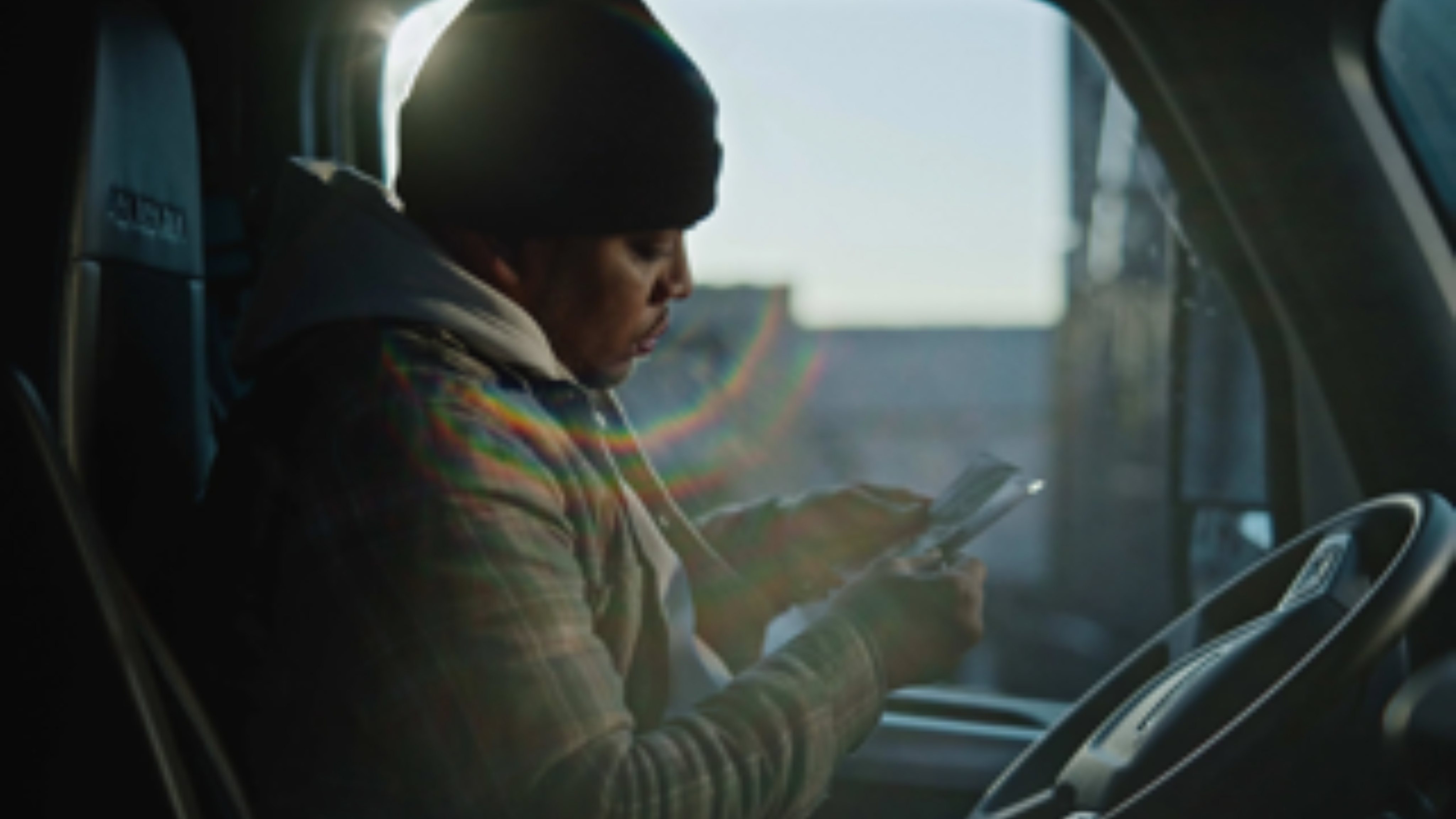 A man sits in his truck cabin reading a note, illuminated by the morning sun.