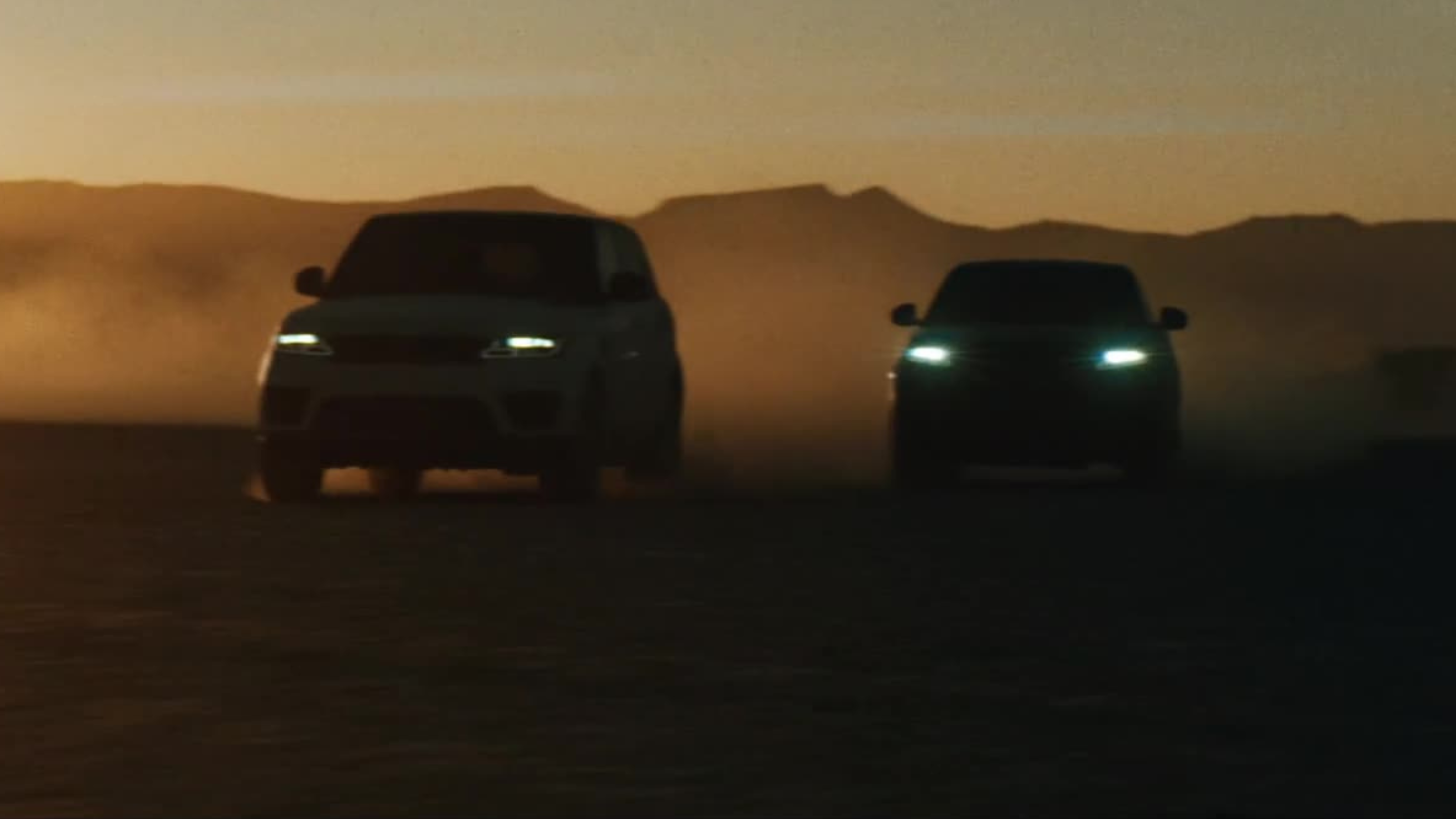 Two SUVs race across a desert at golden hour, creating a dramatic dust trail in cinematic light.