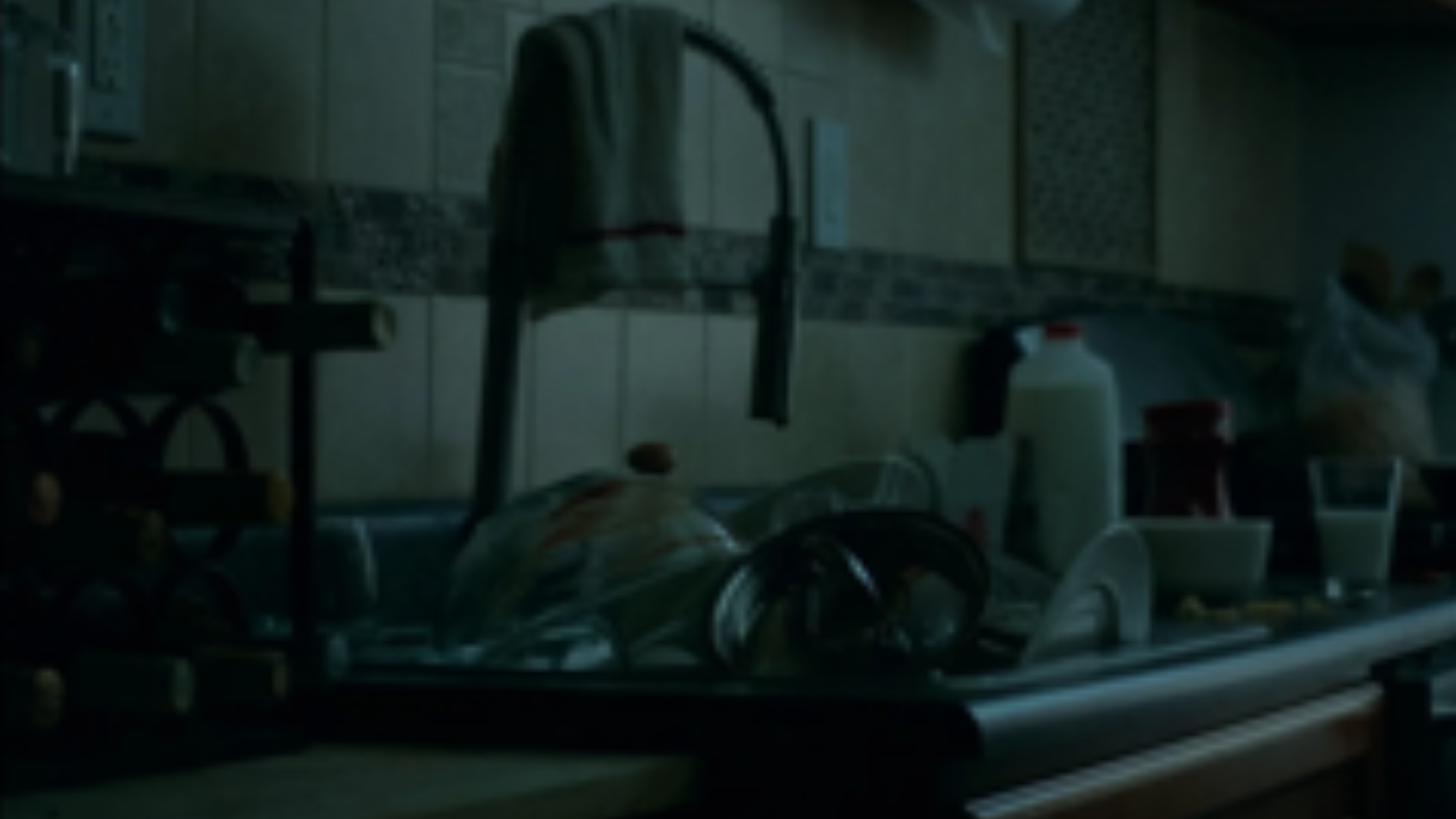 A moody kitchen scene with dishes and morning light, evoking realism and everyday life.