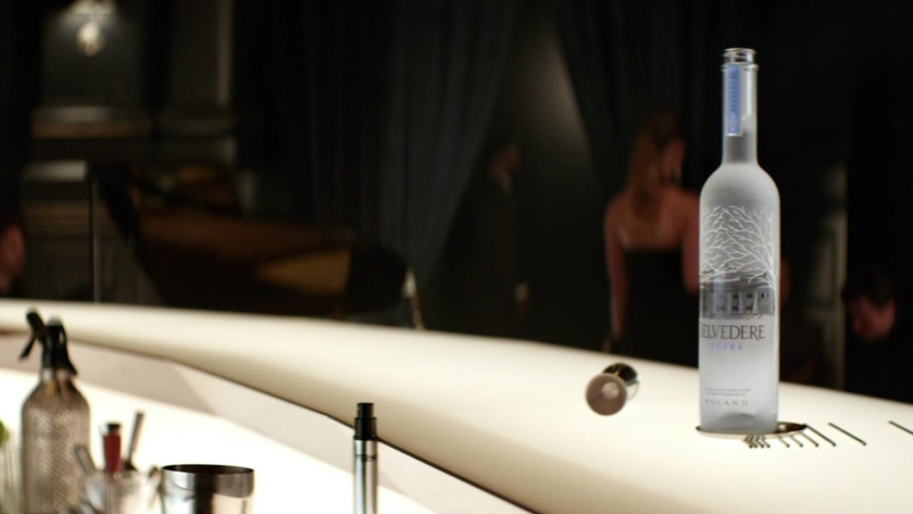 A bottle of Belvedere Vodka sits center stage on a sleek bar as shadows of intrigue and elegance unfold in the background.