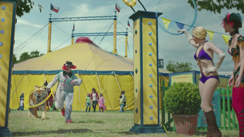 A clown with a tiger charges through a circus entrance as chaos unfolds, highlighting JBL’s wireless audio liberation with surreal humor.
