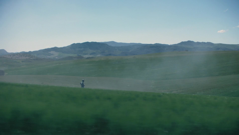 A lone runner traverses open green fields beneath a blue sky, evoking clarity, freedom, and the meditative power of movement.