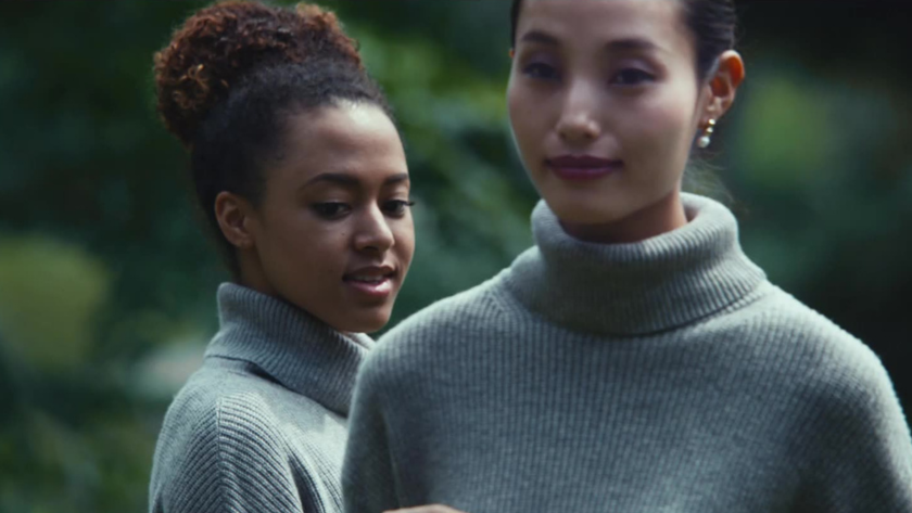 Two women in matching turtlenecks share a quiet moment in nature, radiating calm, closeness, and modern minimalism