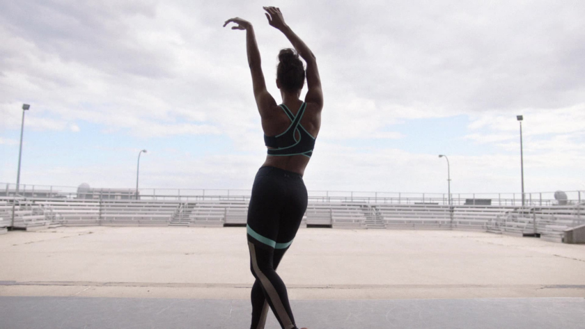 Ballerina Misty Copeland strikes a powerful pose on an empty stadium stage, symbolizing discipline, strength, and solitude.