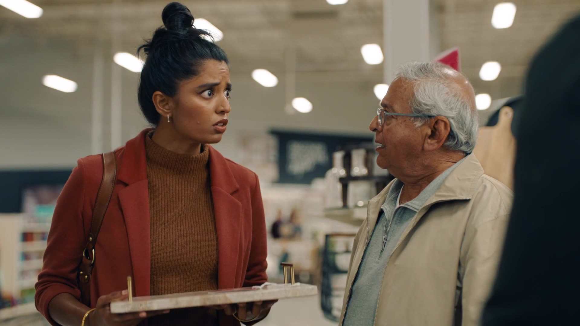 A young woman and an older man share a warm exchange over a tray in a retail store.