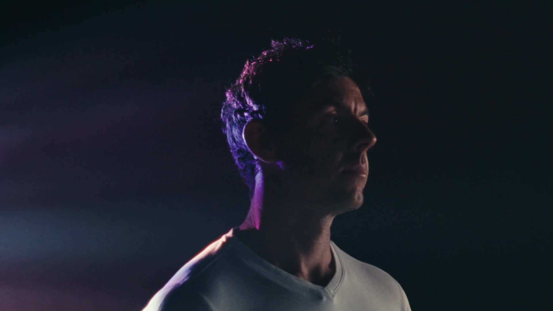 Dramatic profile portrait of an athlete lit in blue and purple against a dark background.