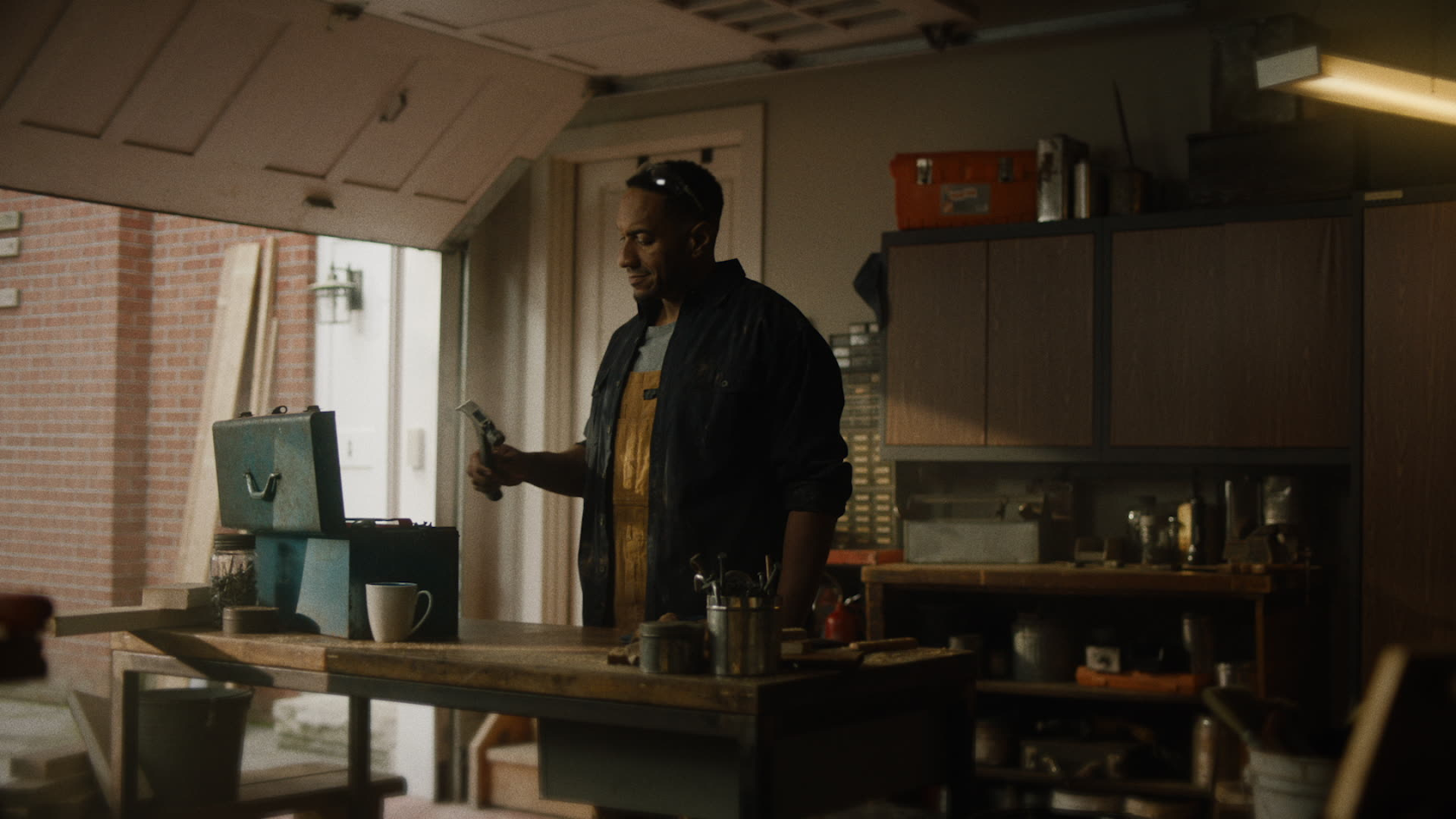 Morning domestic scene of a man checking his phone in a modest kitchen, captured with natural lighting and authentic production design.