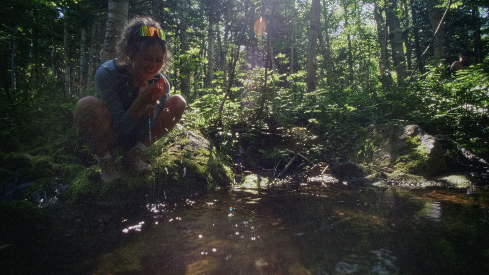 Joyful lady discover nature together in sun-dappled forest stream, shot with warm natural light and authentic documentary style.