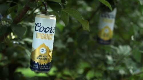 Coors organic cans hanging from a tree branch like a fruit