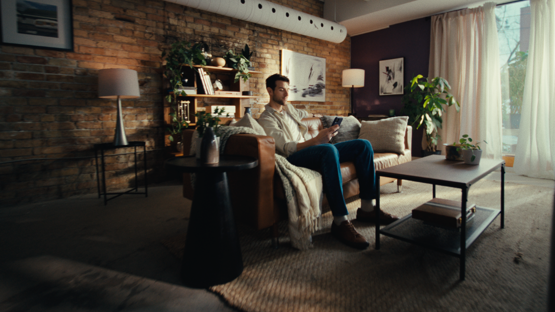 This wide lifestyle frame uses natural light and modern set design to showcase fintech convenience in a cinematic home environment.