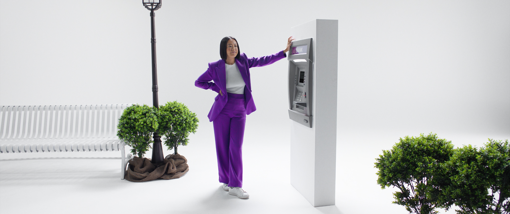 The woman, dressed in a chic purple ensemble, stands by the ATM, patiently waiting for it to respond.