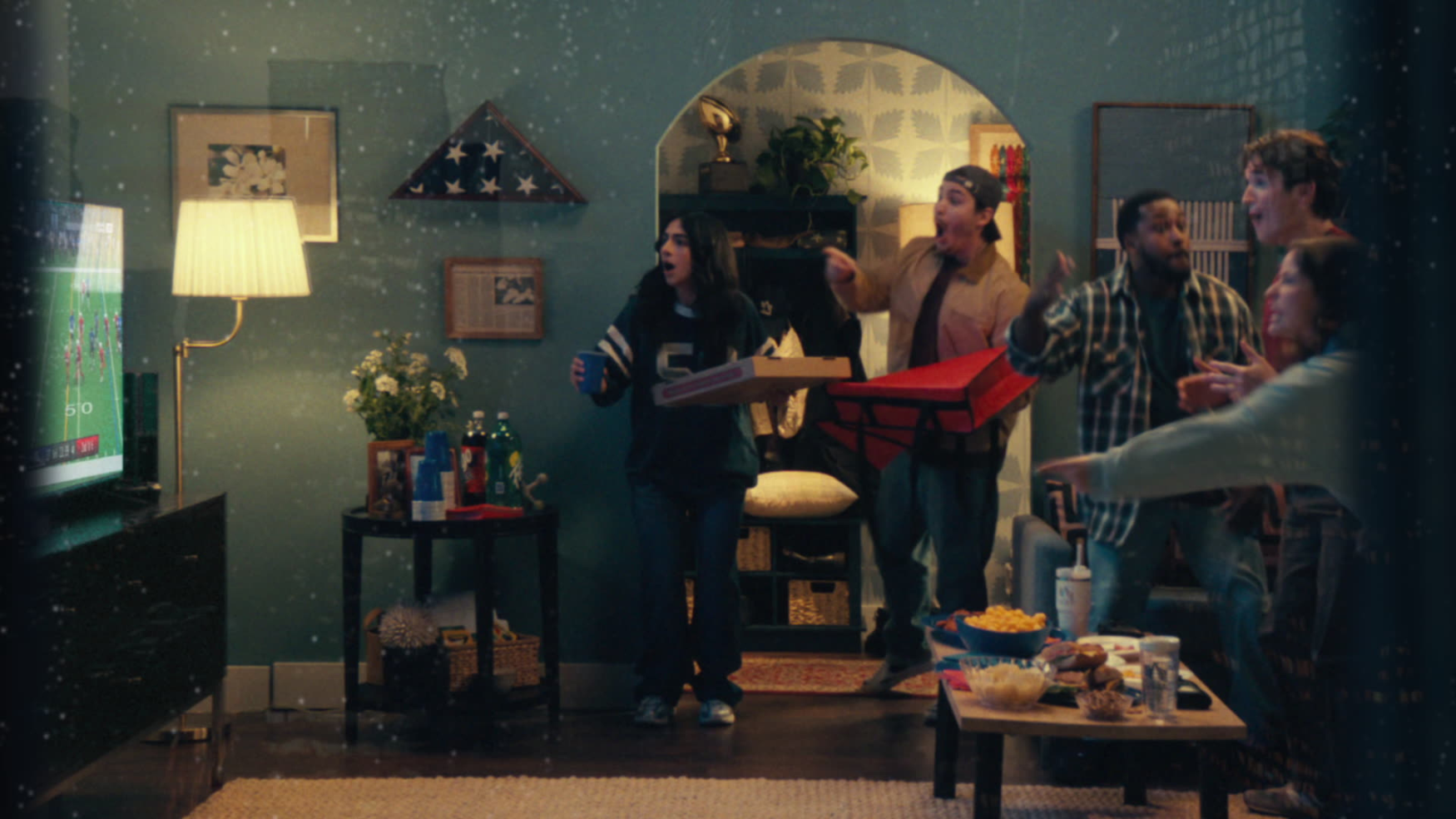Friends and family celebrate together in a cozy, warmly lit living room.