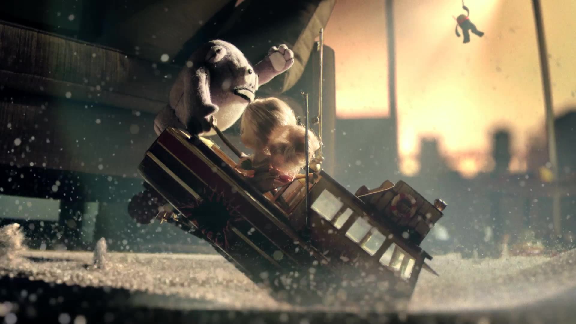 A toy train tilts off the tracks in a rain-soaked, cinematic scene as plush toys cling to it against a glowing city backdrop.