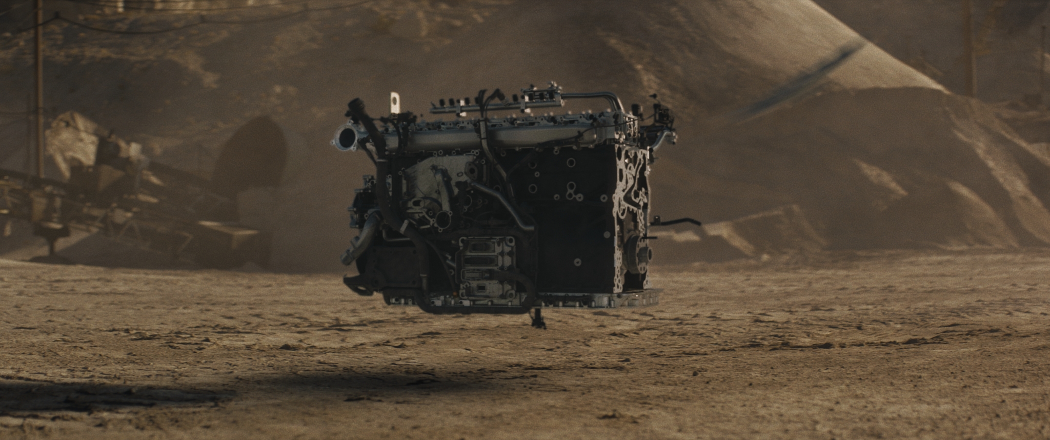 A photo of a transport truck engine, hovering in the air, surrounding by dirt piles. 