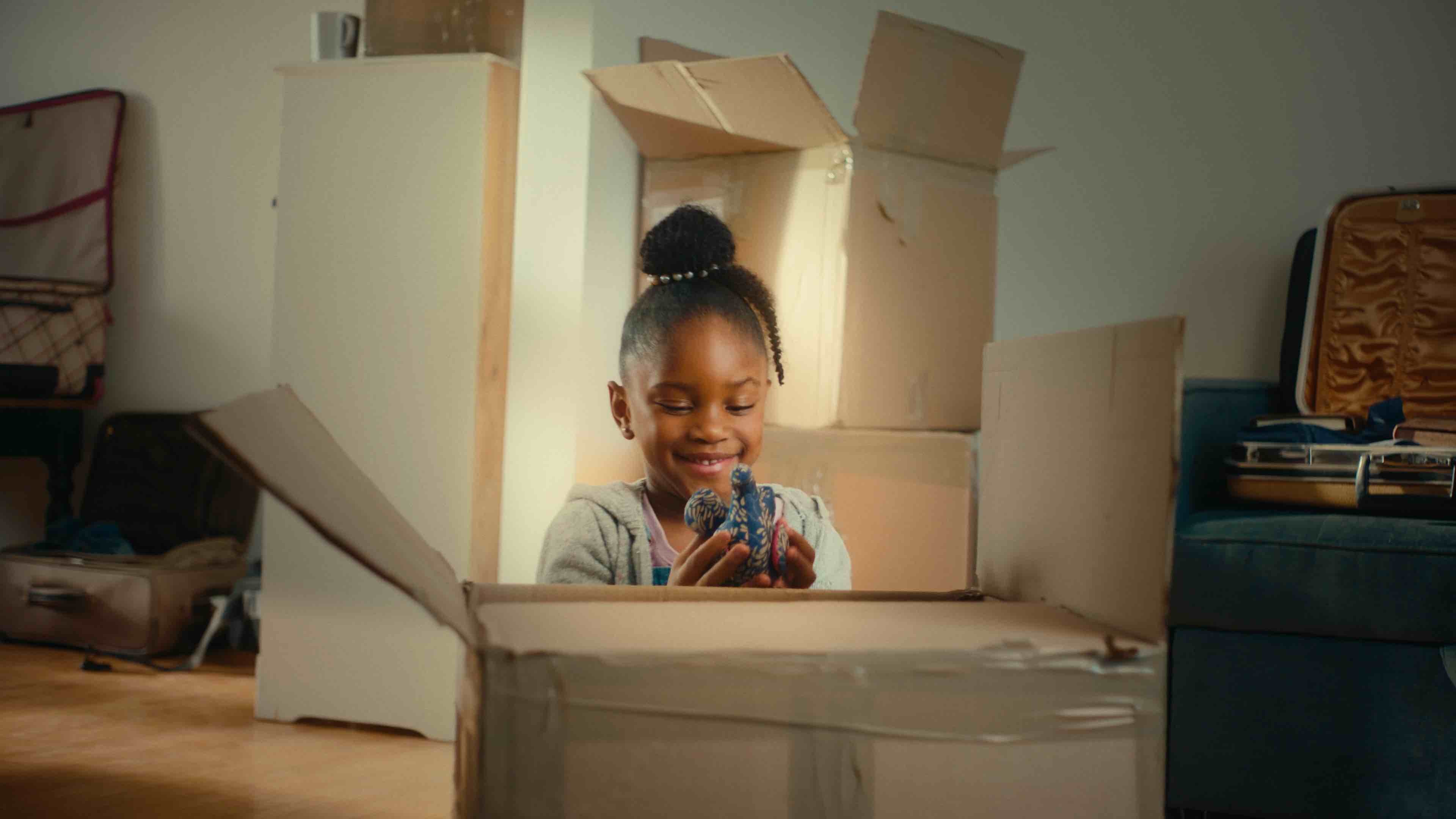 Joyful child unboxing her belongings in their new home